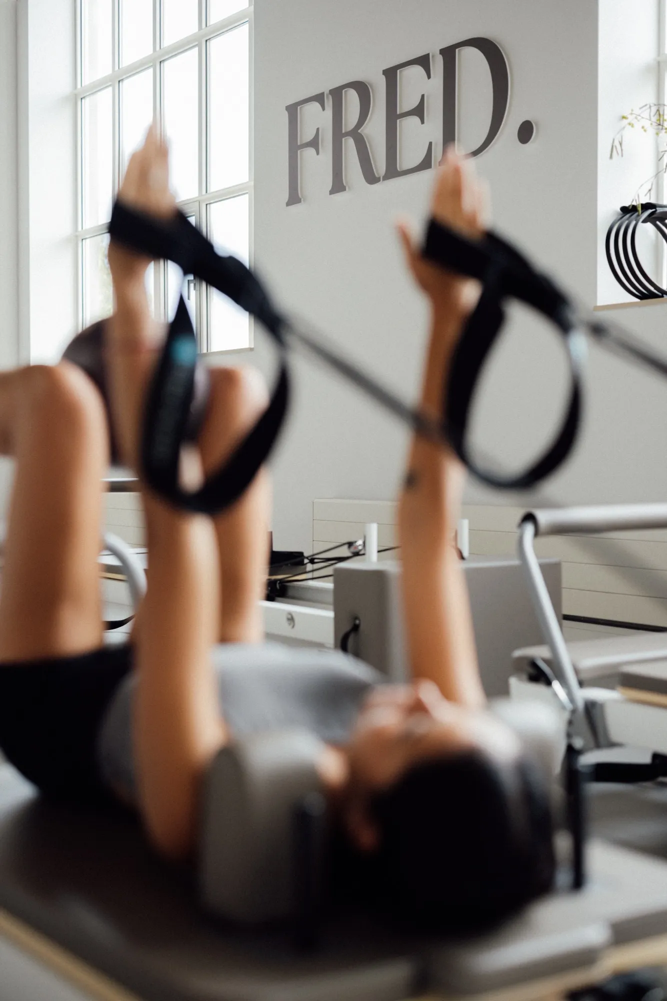 Deelnemers trainen met Pilates-ringen op de Reformer tijdens een Sculpt les bij FRED.